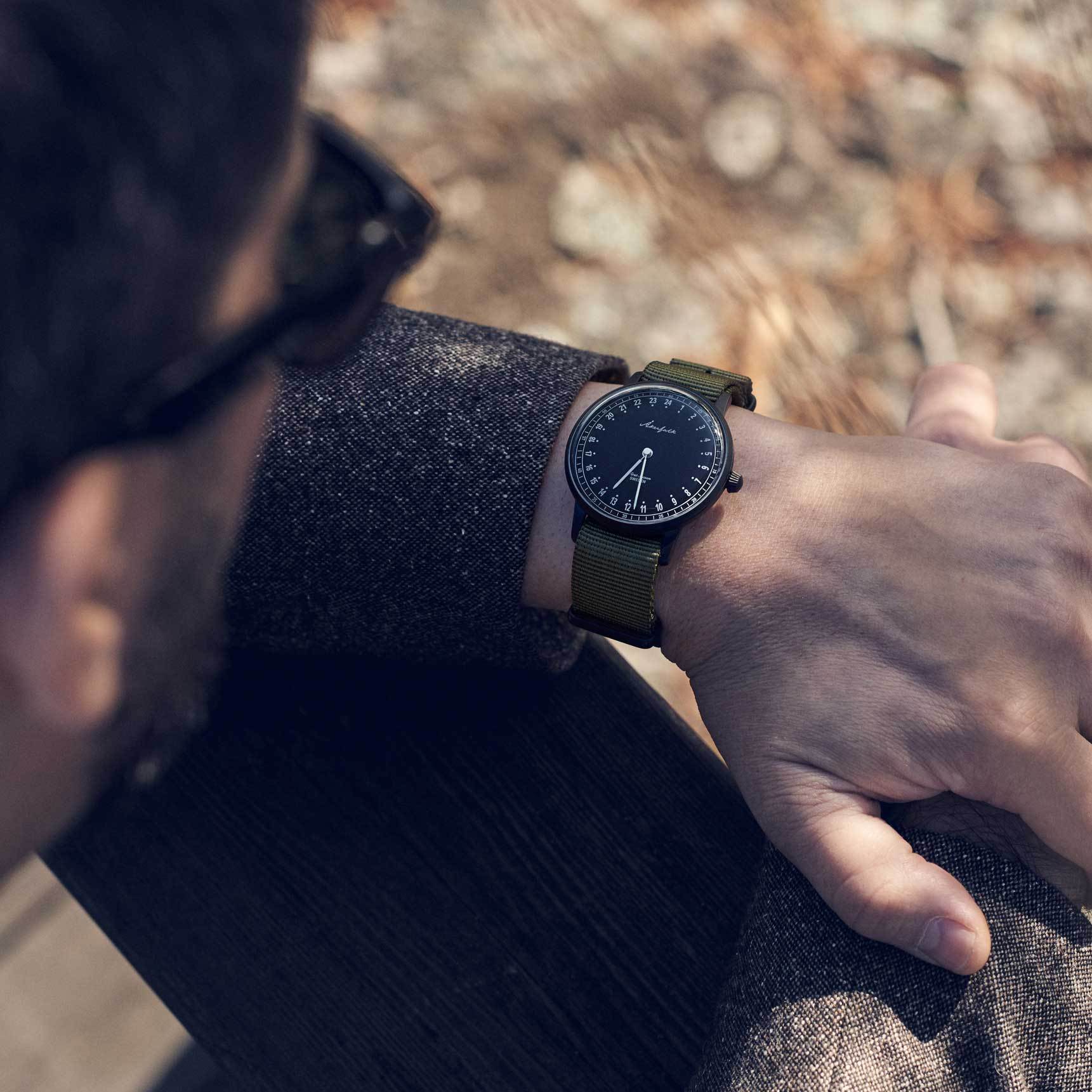 24-hour watch with matte black case and green NATO strap